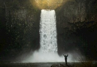 人立于壮观瀑布前景象