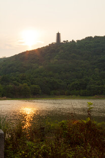 夕阳下湖边山丘上的塔景