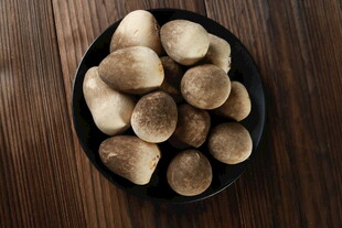 木桌上黑盘中的新鲜蘑菇草菇