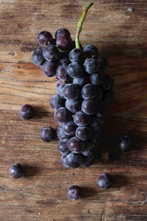 木桌上的紫黑葡萄浆果