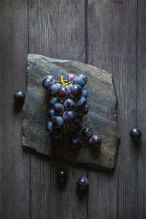 石板上的紫葡萄与散落果粒