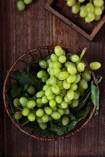 木桌上篮子里的鲜绿葡萄