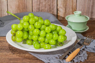 一盘鲜绿葡萄摆于木桌