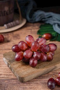 新鲜紫葡萄摆放在木砧板上