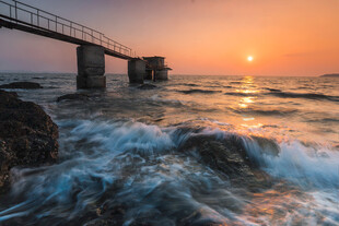夕阳下海边栈桥与浪花