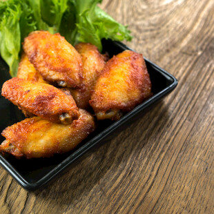 美味烤鸡翅摆于黑色盘上