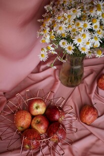 粉布上的苹果与雏菊插花