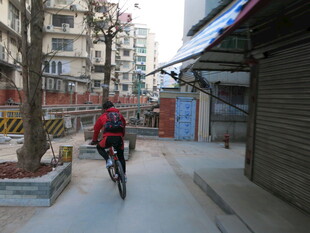 男子骑行于城市小巷