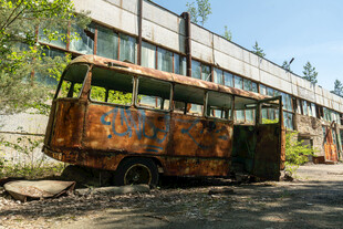 废弃巴士停于破旧建筑旁