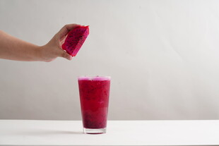 手倒红色饮品入玻璃杯