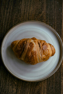 木桌上白盘里的美味羊角包