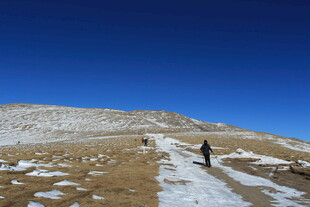 徒步者在雪覆山坡上行进
