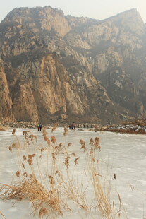 冬日山景下的冰面与枯草