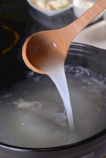 木勺搅拌锅中白色液体