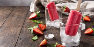 草莓冰棍置于玻璃杯旁