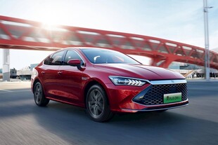 红色轿车驰骋于现代建筑旁