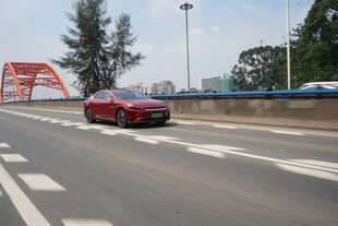 红色轿车行驶在宽阔道路上