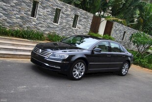 豪华黑色轿车停于石墙旁