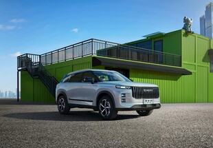 银灰色SUV停于绿墙建筑前