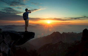 悬崖边迎日出的孤独旅人