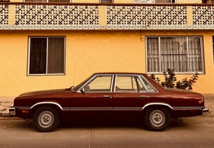 复古轿车停靠在黄色建筑旁