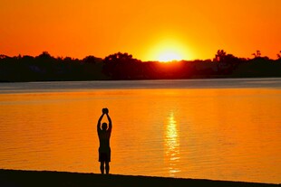 夕阳下湖边的瑜伽冥想者