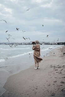 女子海边漫步与飞鸟相伴