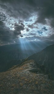 乌云下穿透光芒的山间景色