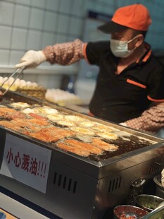 街头烤肠摊主忙碌烤制中