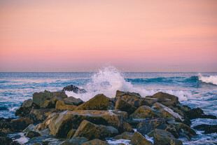 夕阳下海浪拍打礁石美景