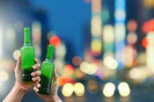 手持绿啤酒瓶的城市夜景