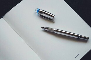 精致钢笔置于翻开笔记本上