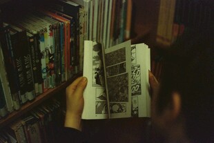 在书架前专注阅读的人