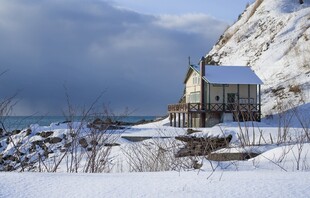 雪覆海岸边的温馨小屋