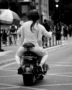女子骑摩托穿行于城市街道