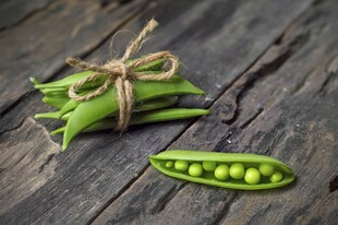 新鲜豌豆摆放在古朴木桌上