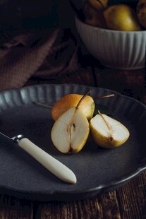 黑盘上的切片梨与刀具