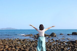 海边女子舒展双臂赏美景