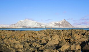海边嶙峋岩石与远处雪山