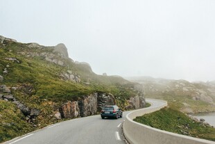 山间雾中蜿蜒公路上的车