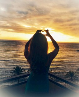 海边女子夕阳下比心剪影