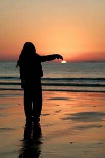 海边剪影女孩指向落日