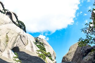 巍峨山石间的蓝天绿树