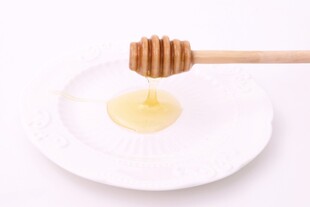 蜂蜜从木勺滴落在白盘上