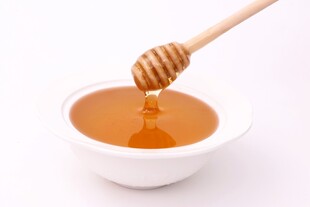 蜂蜜从木勺滴入白碗中