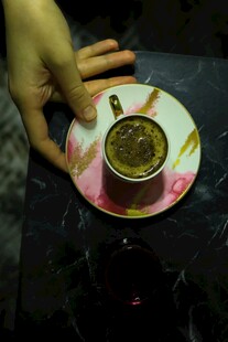 手托精美花纹杯碟中的咖啡