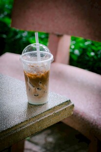 户外木桌上的透明塑料杯咖啡
