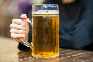 手持大杯畅饮金黄啤酒