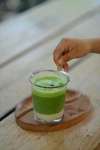 手递抹茶饮品于木桌