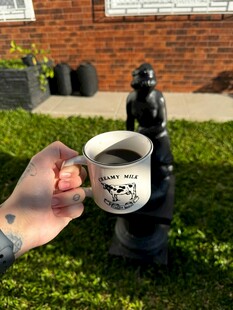 手持咖啡杯与雕像的场景
